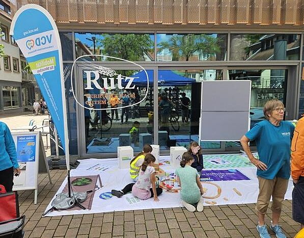 Vier Kinder spielen auf dem VCD-Bodenbanner mit der Holzeisenbahn