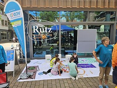 Vier Kinder spielen auf dem VCD-Bodenbanner mit der Holzeisenbahn
