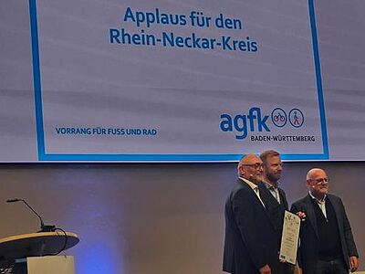 AGFK-Vorsitzender Günter Riemer und Verkehrsminister Winfired Hermann übergeben die Urkunde an einen Vertreter des Rhein-Neckar-Kreises