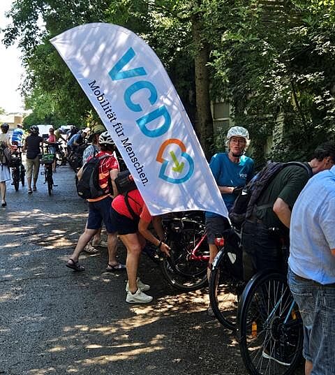 Mehrere Mitradelnde beim Abstellen der Fahrräder, groß im Vordergrund die VCD-Fahrradbeachflag