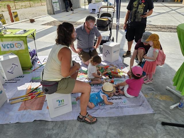 Familie mit vier kleinen Kindern beim Spiel mit Hozspielzeug unter dem Pavillon auf unserem Bodenbanner
