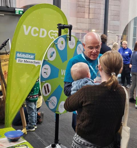 Interessierte Mutter mit Baby auf dem Arm am VCD-Glücksrad