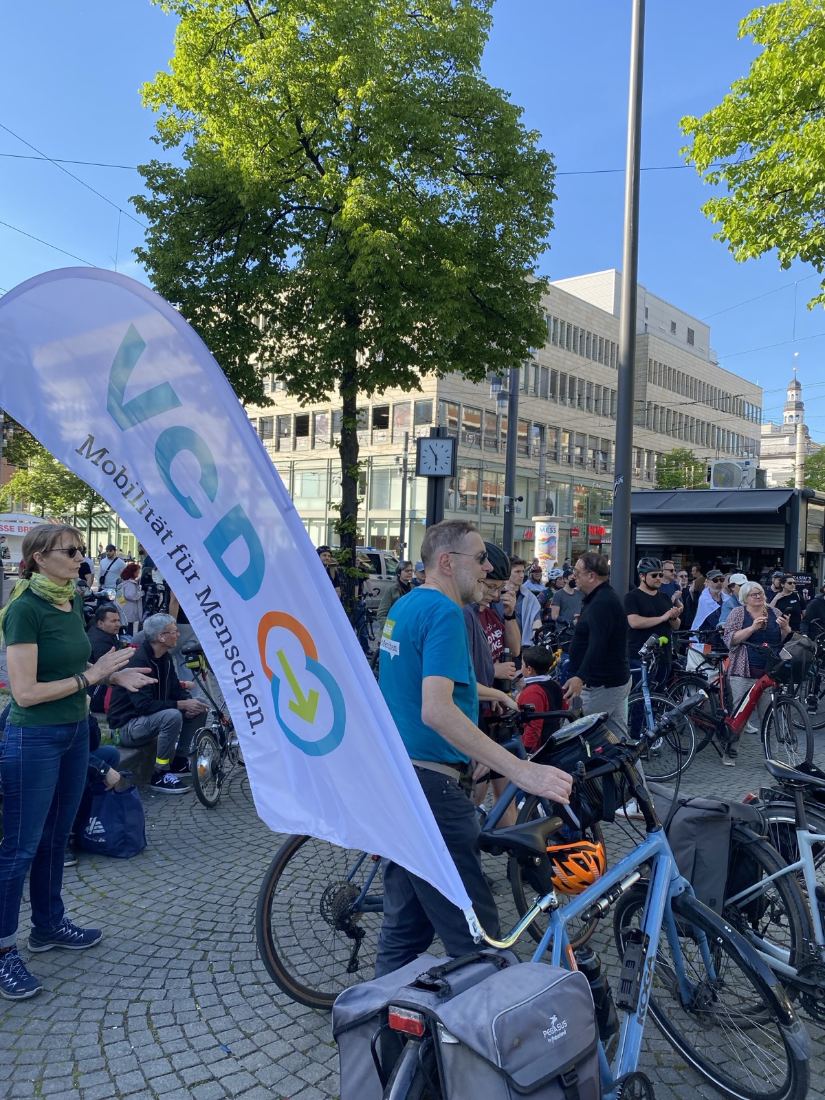 Im mVordergrund VCD-Aktiver mit großer VCD-Fahne am Fahrrad; im Hintergrund die Masse Teilnehmender an der Farraddemo