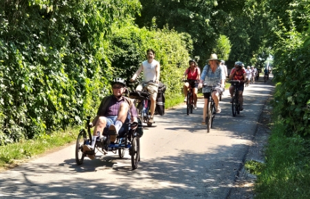 Ein Pulk Mitradelnde auf dem Weg zwischen hohen Hecken